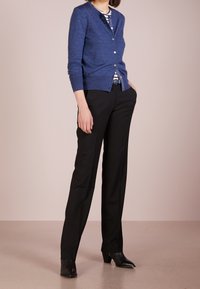 Blå ullkofta med rund halsringning, knappstängning och långa ärmar, tillsammans med svarta skräddarsydda byxor och svarta klackade ankelskor.