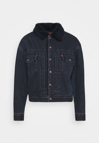 Mörk denimjacka med ett fårskinnskrage, knappstängning, två bröstfickor och en kortad silhuett med synliga sömdetaljer.