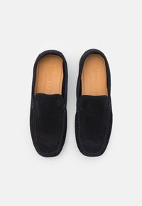 Marineblaue Wildleder Slipper mit kontrastierenden Nähten, runder Zehenform und einem weichen Innenfutter aus hellbraunem Leder. Glatte Textur über die gesamte Oberfläche.