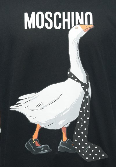 Čierne tričko s kreslenou husou, ktorá nosí čiernu kravatu s bodkami a čierne topánky, s nápisom "MOSCHINO" nad obrázkom bielymi písmenami.