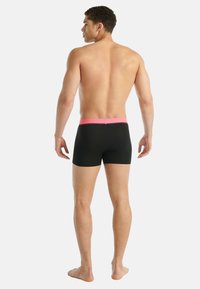 Czarne bokserki z teksturowanym różowym pasem, dopasowanym krojem i gładkim materiałem, widoczne z tyłu na modelu.