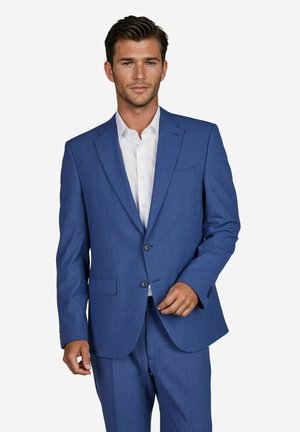 Herrenanzug in Blau aus strukturiertem Stoff mit zwei Knöpfen, einem Reverskragen und seitlichen Taschen. Getragen über einem weißen Hemd.
