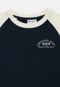 Μπλουζάκι σε σκούρο μπλε χρώμα με μπεζ μανίκια ράγκλαν, από βαμβακερό ύφασμα, με κεντημένο το λευκό κείμενο "Southern State 315 Physical Education".