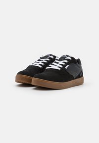 Czarne zamszowe i syntetyczne sneakersy z białymi sznurówkami, gumową podeszwą i logo na języku oraz bocznej ściance. Niski krój.