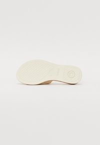 Semelle d'une chaussure beige avec grip texturé, motif circulaire au talon et nom de la marque "Gabor" visible sur un fond blanc.