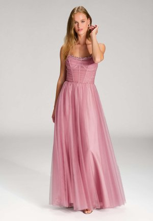 Abito lungo in tulle rosa con corpino aderente, dettagli arricciati e scollatura gioiello. La gonna scorre elegantemente fino a terra.