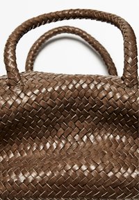 Borsa a tracolla in pelle intrecciata marrone con manici a treccia. Presenta una superficie strutturata e una forma definita, evidenziando l'artigianato e i dettagli.