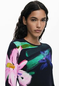 Long-sleeved top featuring a dark background with vibrant floral patterns in pink, green, and blue. Soft, smooth fabric texture.
