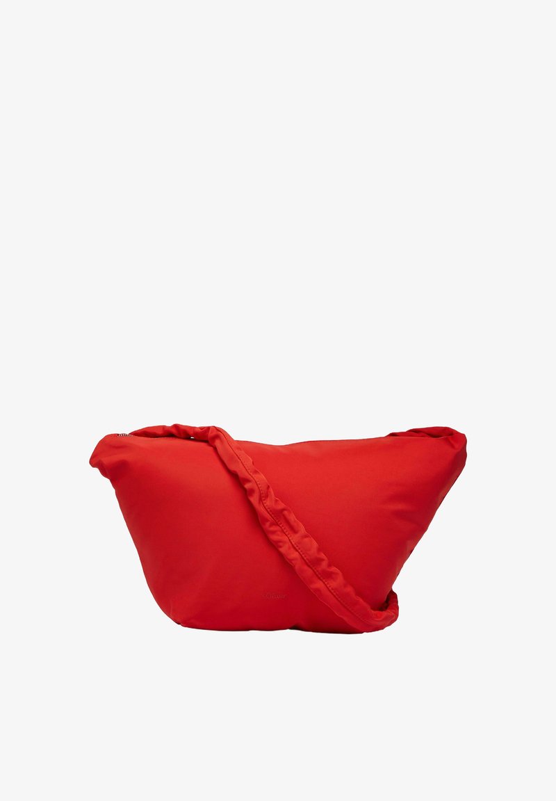 Czerwona torba na ramię o trójkątnym kształcie, z zamkiem błyskawicznym i falbanowym paskiem. Powierzchnia wydaje się gładka i miękka.