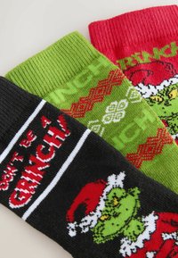 Tričko s troma ponožkami: čierne s nápisom "Nemôže byť Grinch", zelené so snehovými vločkami, červené s ilustráciou Grincha. Všetky sú rebrované a farebné.