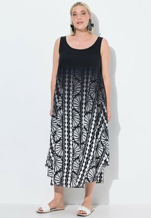 Schwarz-weißes Maxi-Kleid mit rundem Ausschnitt, das ein Farbverlauf-Design, kräftige Blattmuster und diagonale Streifen aufweist. Gleiche Stofftextur.