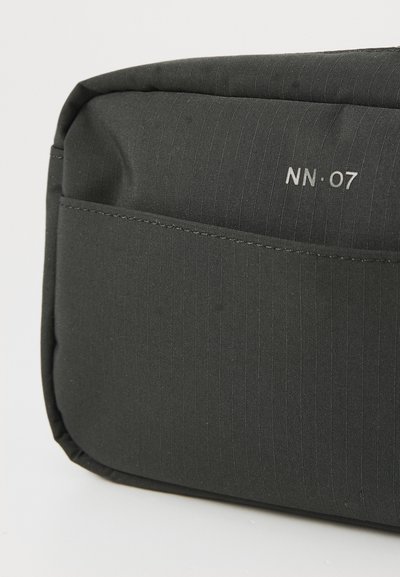 Bolsa de tela negra con una textura suave, que presenta un patrón de rayas horizontales y un bolsillo lateral. Incluye la marca "NN·07" en plata.