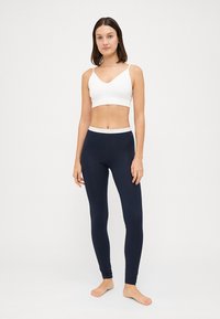 Vit cropped tanktop med tunna band som matchas med marinblå leggings. Tyget ser slätt, elastiskt och åtsittande ut, med ett kontrasterande midjeband.
