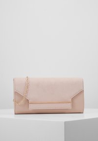 Pudrově růžové psaníčko z semiše a strukturované kůže se zlatým řetízkem přes rameno. Má úhlovou klopu a zlatý dekorativní proužek.