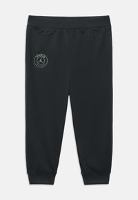 Schwarze Sporthose mit elastischem Bund und Bündchen. Auf dem linken Oberschenkel befindet sich ein runder Logoaufdruck mit dem Schriftzug "PARIS SAINT-GERMAIN".