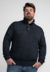 Donkerblauwe gebreide trui met een hoge kraag, voorzien van drie knopen en geribde manchetten en onderkant. Gladde textuur met subtiele patroonvariaties.