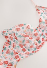 Bh med lyserødt, gennemsigtigt stof med jordbær- og blomsterprint. Den har formstøbte skåle og delikate sømme langs kanterne.