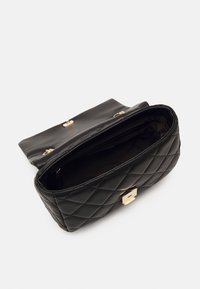 Gepunktete schwarze Lederhandtasche mit goldenen Beschlägen. Öffnet sich zu einem geräumigen Innenraum. Verfügt über einen umklappbaren Deckel und einen rechteckigen Verschluss.