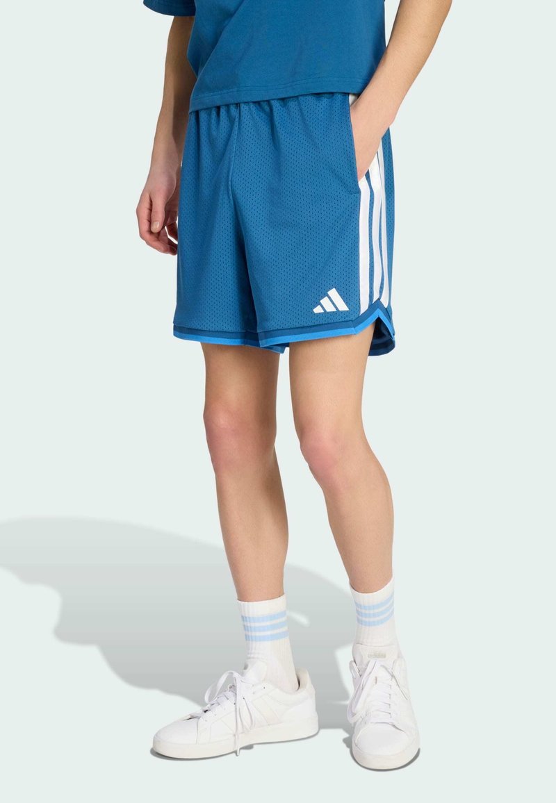Shorts de sport en mesh bleu avec un design à trois bandes blanches, taille élastique et poches latérales. Portés avec des baskets blanches et des chaussettes rayées.