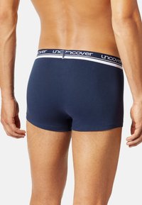 Marina blå boxershorts i mjukt material, med ett brett elastiskt midjeband med vit "uncover"-logotyp. Tätt sittande design.