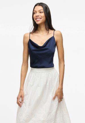 Navy satin camisole with a cowl neckline and thin straps, paired with a white embroidered A-line skirt featuring a gathered waistband.