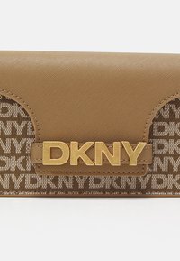 Portofel maro DKNY cu un finisaj texturat saffiano, având un închizător cu logo auriu și o țesătură cu un model ce include numele mărcii.
