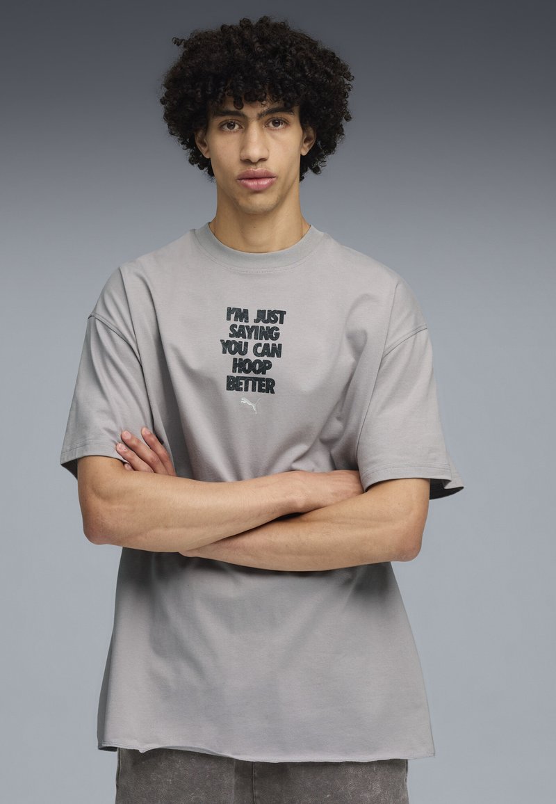 Camiseta de algodón gris con mangas cortas, con un diseño de texto en negro: "SOLO DIGO QUE PUEDES JUGAR MEJOR" y un pequeño logo.