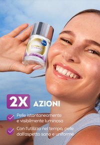 La lozione NIVEA Luminous Skin Glow in una bottiglia di vetro trasparente con un tappo argentato. L'etichetta presenta accenti gialli e viola. Lo sfondo è un cielo blu.