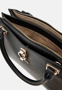 Borsa a tracolla in pelle nera con superficie texturizzata, hardware dorato e molteplici scomparti interni. Chiusura con zip e logo in evidenza sulla parte anteriore.