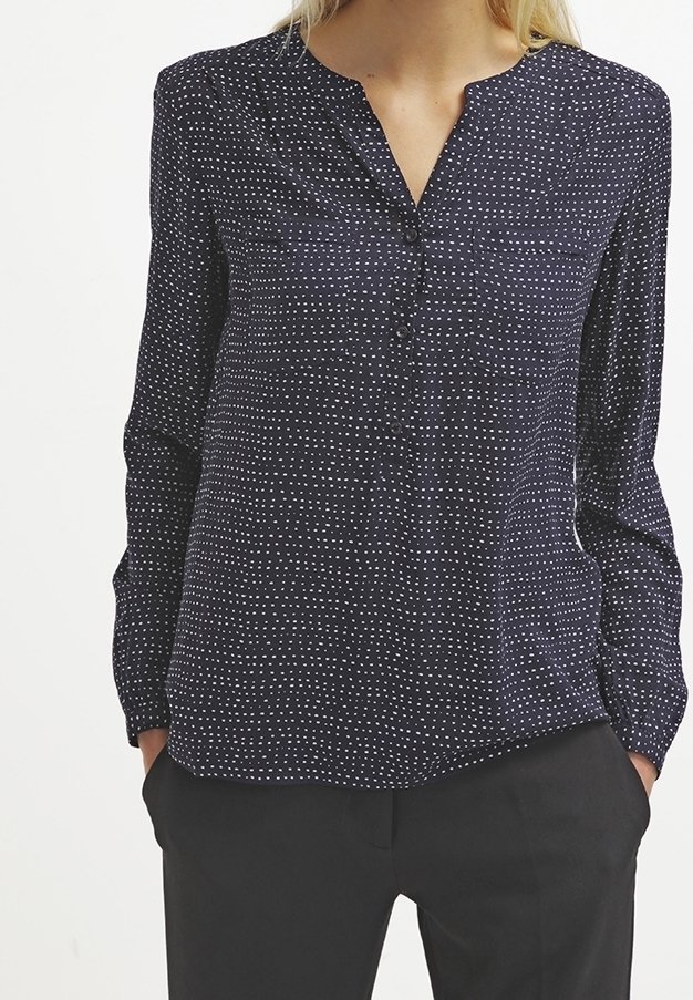 Blusa blu navy con un sottile motivo a pois bianchi, con chiusura a bottoni e maniche lunghe. Realizzata in un tessuto leggero e morbido.