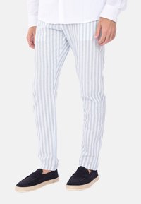 Pantaloni in lino a righe azzurre e bianche con vestibilità slim; abbinati a espadrillas navy con suola in juta intrecciata.
