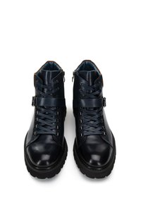 Botas de tobillo de cuero negro con un acabado suave, parte delantera con cordones, doble cremallera y una suela texturizada resistente. Presentan un forro interior azul.