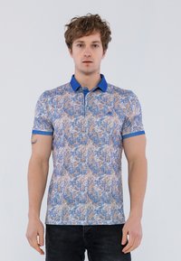 Camisa polo azul con un patrón texturizado en tonos de beige y marrón, que presenta un color de cuello azul en contraste y mangas cortas.