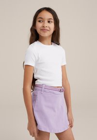 Top blanco de manga corta con relieve, combinado con una falda lila que presenta un cinturón texturizado y bolsillos. Costuras expuestas visibles.