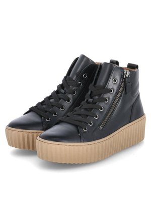 Schwarze Leder-High-Top-Sneaker mit dicken gerippten hellbraunen Sohlen, schwarzen Schnürsenkeln und seitlichen Reißverschlüssen, schräg auf weißem Hintergrund gezeigt.
