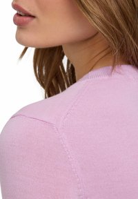 Helles rosa Strickpullover mit glatter Textur, detaillierten Schulternähten und tailliertem Design, von hinten und der Seite gezeigt.