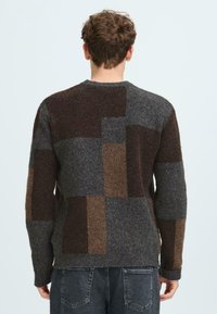 Herren-Wollpullover mit einem Patchwork-Design in Grautönen, Braun und Rost. Weiche Textur mit gerippten Bündchen und Saum.