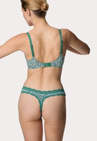 Zelená souprava spodního prádla obsahující podprsenku a tangá, s leopardím vzorem, krajkovým lemem a nastavitelnými ramínky pro dokonalé přizpůsobení.
