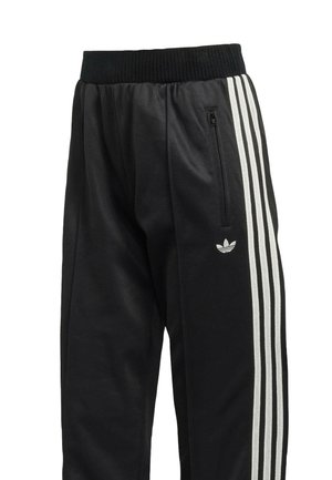 Pantalon de sport noir avec une ceinture côtelée, comportant trois bandes verticales blanches sur les côtés et une poche zippée sur la cuisse gauche.