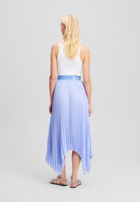 Gonna plissettata di color azzurro chiaro con orlo asimmetrico. Realizzata in tessuto morbido, presenta una vita liscia e una trama delicata.