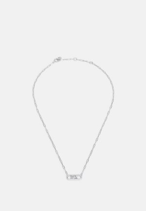 Collier en chaîne argentée avec pendentif rectangulaire comportant les initiales « MK » et de petits cristaux incrustés sur fond blanc.