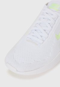 White athletic shoe with a textured mesh upper, featuring white laces and a neon green swoosh logo on the side.