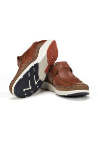 Zapatos de piel marrón slip-on con suela blanca y azul marino, que cuentan con detalles cosidos y acentos elásticos laterales para un fácil uso.