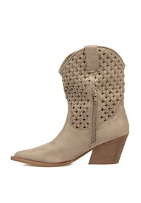 Bota de cowboy de ante beige con un diseño superior trenzado, punta afilada, cremallera lateral y un tacón de madera de mediana altura. Superficie texturizada con detalle de costura.