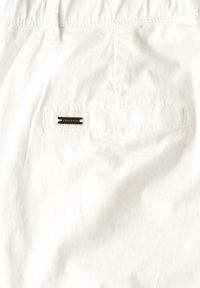 Shorts bianchi in cotone con una tasca posteriore dotata di un'etichetta metallica. Il tessuto presenta una finitura leggermente texture. Inclusa una fascia elastica in vita.