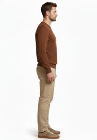 Suéter de punto marrón, pantalones beige y zapatillas marrones. El suéter tiene un escote redondo y puños acanalados. Los pantalones son a medida.