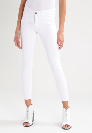 Hvide denim skinny jeans med høj talje, fem-lomme design og diskret falmet detalje, kombineret med hvide peeptoe-ankelstøvler.