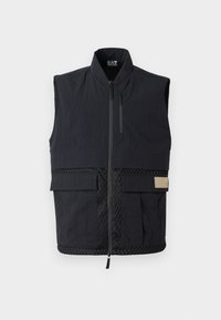 Black sleeveless vest with a high collar, textured fabric, front zipper, and two large pockets. Features mesh detailing at the waist.