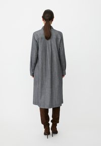 Szara sukienka koszulowa do kolan z długimi rękawami, prostym krojem i subtelnym wzorem w prążki. Uzupełniona brązowymi kozakami za kolano.