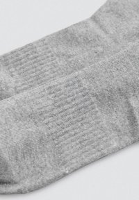 Calcetines de algodón gris con un patrón acanalado, que presentan una textura suave y un diseño sin costuras en la puntera para mayor comodidad.